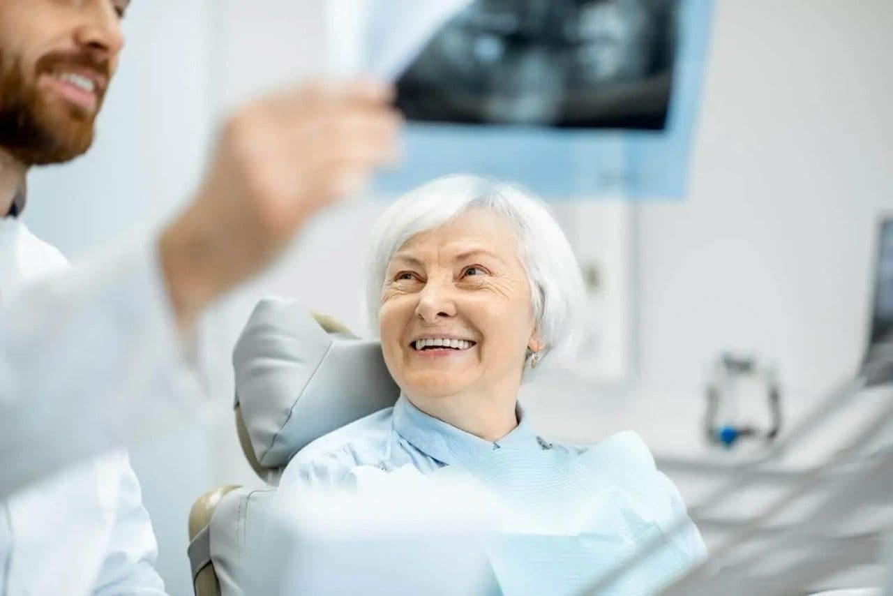 An elder female patient smiling at her dentist