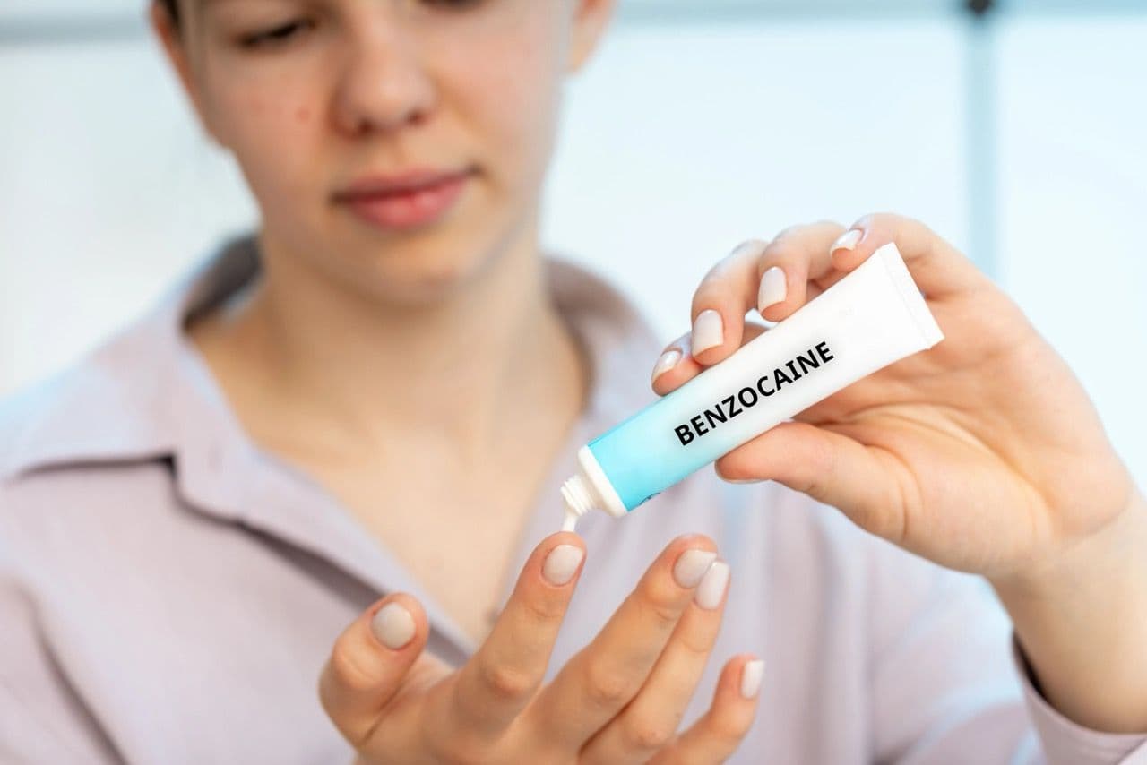 A woman applying benzocaine to her fingertip