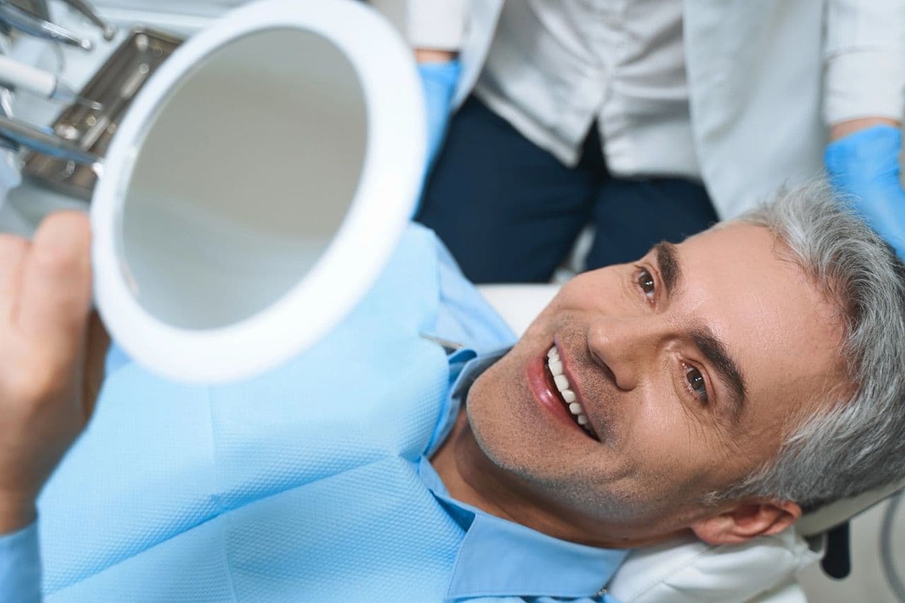 Photo of a patient examining the results of dental implants
